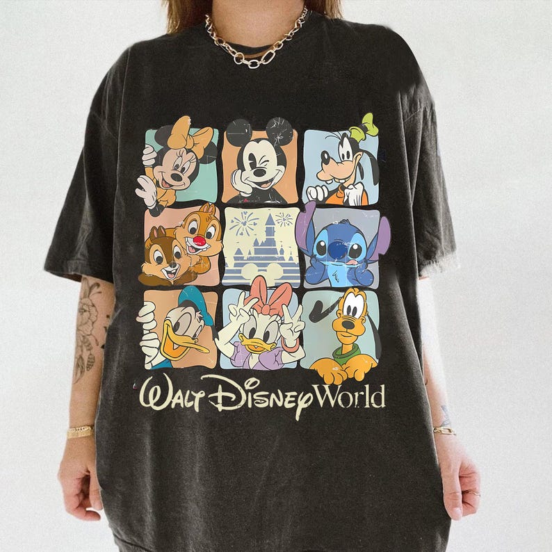Puede incluir: Camiseta negra con una colorida cuadr&iacute;cula de personajes de Disney, incluyendo Mickey Mouse, Minnie Mouse, Goofy, Donald Duck, Daisy Duck, Chip y Chop, Stitch y un castillo. Las palabras "Walt Disney World" est&aacute;n impresas debajo.