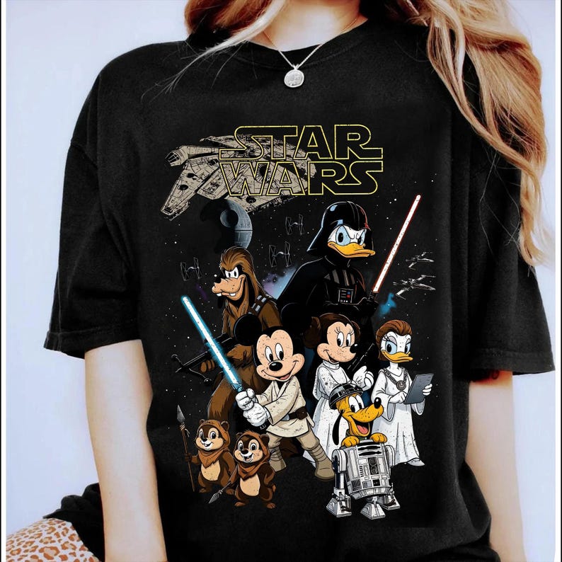 May include: Black t-shirt featuring a Star Wars graphic with Disney characters. The design includes Mickey Mouse, Minnie Mouse, Donald Duck, Daisy Duck, Goofy, Pluto, Chip and Dale, and R2-D2, with a Star Wars logo.