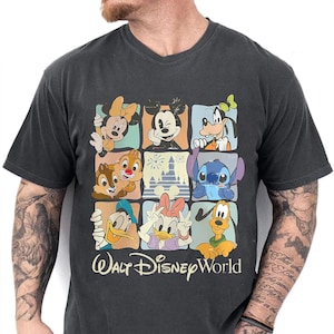 Puede incluir: Camiseta gris oscuro con cuello en V que presenta una colorida cuadr&iacute;cula de personajes de Disney, incluyendo Mickey Mouse, Minnie Mouse, Goofy, Donald, Daisy, Chip y Chop, Stitch y Pluto. Las palabras "Walt Disney World" est&aacute;n impresas debajo.