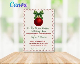 May include: A festive baby shower invitation with a Christmas theme. It features a red bauble with a green bow, and the text "A Little Miracle Wrapped In Holiday Cheer". The invitation is on a cream background.