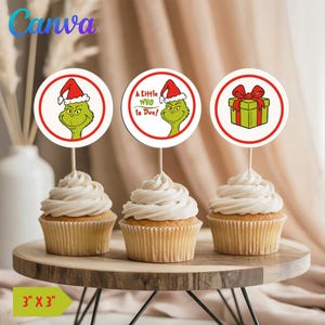 May include: Three cupcakes with white frosting, each topped with a circular decoration featuring a Grinch character or a gift box. The decorations are on wooden sticks. The cupcakes sit on a wooden cake stand.