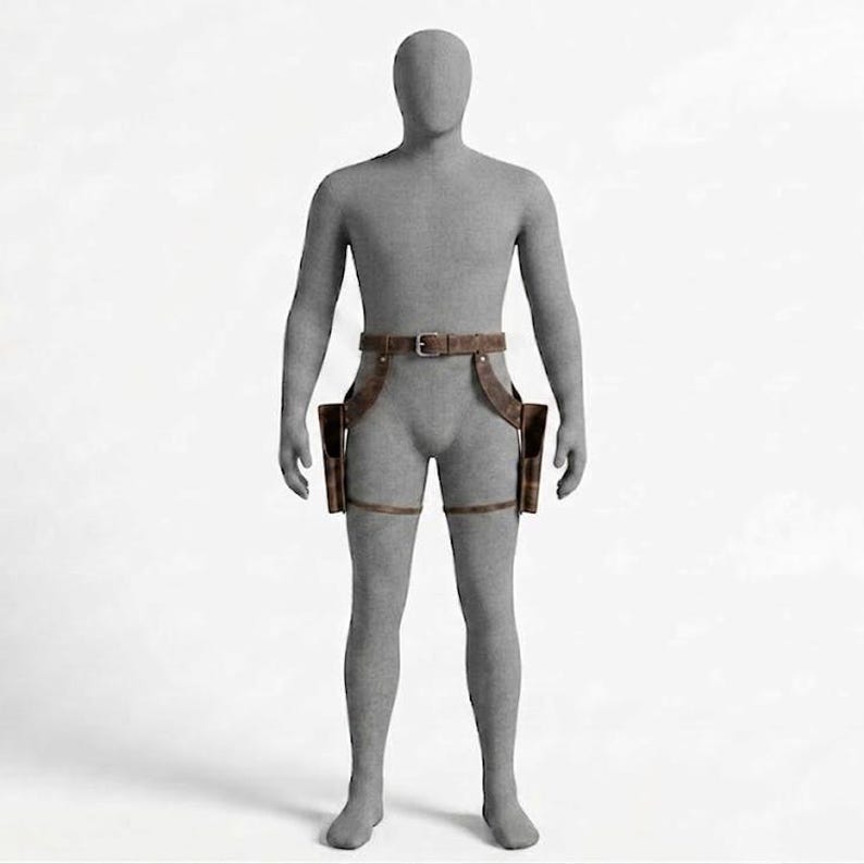 May include: A brown leather dual holster belt system worn on a grey mannequin. The accessory features a waist belt with a metal buckle, two side holsters positioned at the hips, and adjustable leg straps that secure around each thigh for stability.