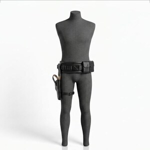 Puede incluir: Un cintur&oacute;n utilitario negro sobre un torso de maniqu&iacute; gris oscuro. El cintur&oacute;n presenta una serie de bolsillos rectangulares, una funda r&iacute;gida unida al lado derecho y una correa fina para la pierna. El dise&ntilde;o incluye compartimentos.