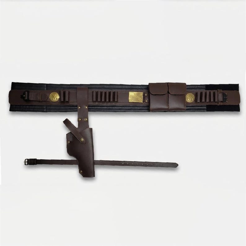 Puede incluir: Un cintur&oacute;n utilitario de cuero marr&oacute;n oscuro que incluye una funda, dos bolsas de almacenamiento y m&uacute;ltiples bucles para munici&oacute;n. El cintur&oacute;n cuenta con una hebilla rectangular de lat&oacute;n, dos emblemas circulares de lat&oacute;n y una correa de pierna.