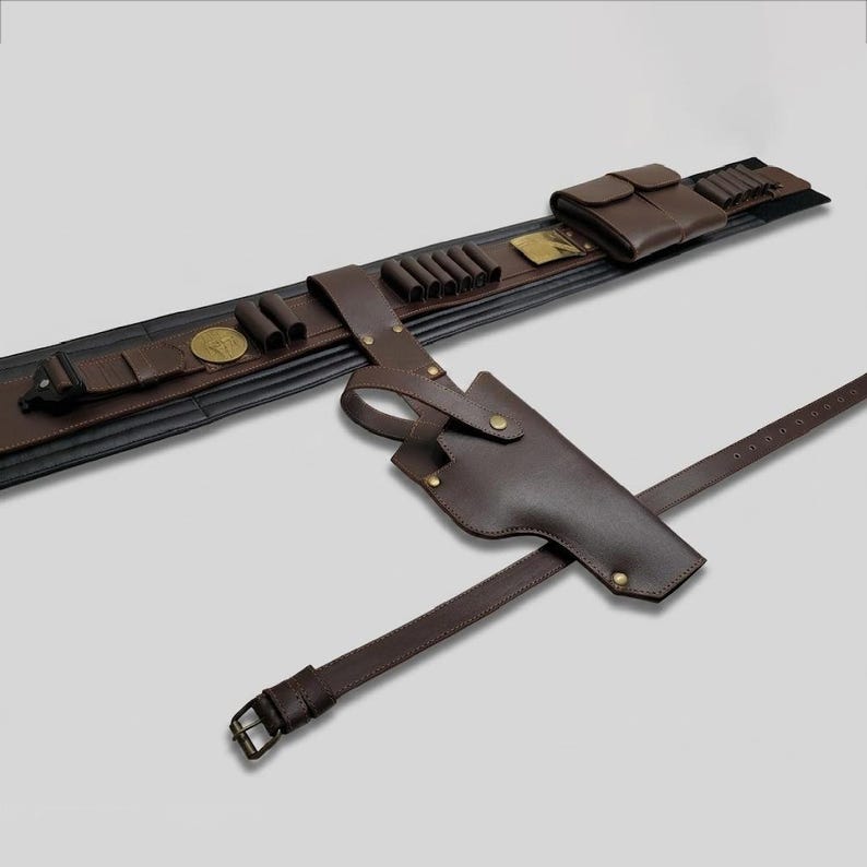 Puede incluir: Un cintur&oacute;n utilitario de cuero marr&oacute;n oscuro que presenta una funda, m&uacute;ltiples bucles para munici&oacute;n, una bolsa rectangular y un emblema circular de tono dorado. El cintur&oacute;n est&aacute; construido con remaches met&aacute;licos y una correa ajustable.