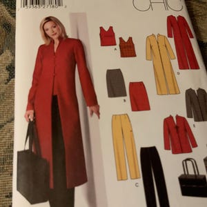 May include: A sewing pattern featuring a woman in a red coat and various garment designs. The pattern includes a long red coat, skirts, pants, and tops in red, yellow, and black. A black tote bag is also shown.