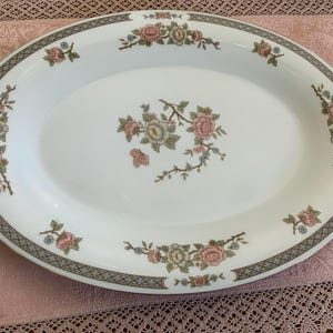 May include: A white oval serving platter with a blue and green floral design. The floral design features pink, white, and green flowers.
