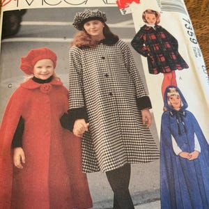 May include: A McCall's 7359 sewing pattern envelope featuring illustrations of three different coats and capes. One is a red cape with a matching beret, another is a black and white houndstooth coat with a dark collar, and one is a blue hooded cape.