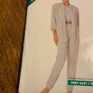 May include: A sewing pattern for a light gray pantsuit with a long-sleeved jacket and wide-leg pants. The pattern is labeled "VERY EASY/TRÈS FACILE" and is from Butterick.