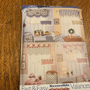 May include: A sewing pattern envelope for reversible valances featuring four distinct window treatment designs labeled A, B, C, and D. The cover displays illustrations of floral and striped fabric valances with bows and scalloped edges in various colors.