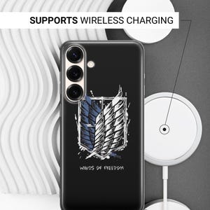Może przedstawiać: Czarne etui na telefon z białym i niebieskim motywem skrzydeł oraz napisem "WINGS OF FREEDOM". Etui jest pokazane z ładowarką bezprzewodową. Widoczne są r&oacute;wnież napisy "SUPPORTS WIRELESS CHARGING" i "SIDES ARE NOT PRINTED".