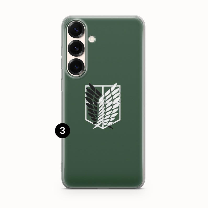 Może przedstawiać: Zielone etui na telefon z biało-czarnym emblematem. Etui ma przezroczystą obw&oacute;dkę i aparat z trzema obiektywami. Emblemat to stylizowany wz&oacute;r skrzydeł w białej obw&oacute;dce.