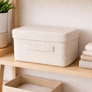 May include: A rectangular storage box with a lid, crafted from off-white woven rope material. The box features a horizontal handle integrated into the front panel, providing a clean and functional design for organizing household items.