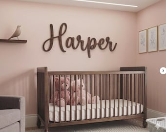 May include: A dark brown wooden wall sign featuring the name Harper in a cursive script font. The sign is mounted on a light pink wall above a dark brown wooden crib containing two plush teddy bears, one dark pink and one light pink.