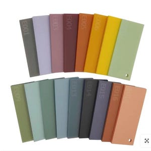 May include: A collection of rectangular color swatches in various shades, including gray, purple, red, orange, yellow, and green. Each swatch is labeled with a code and has a small hole. The swatches are arranged in two rows.