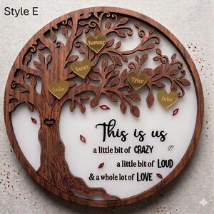 May include: A round wooden family tree wall decor with a dark brown finish. The tree has gold heart-shaped name tags and the text "This is us" with the phrases "a little bit of CRAZY, a little bit of LOUD, & a whole lot of LOVE."