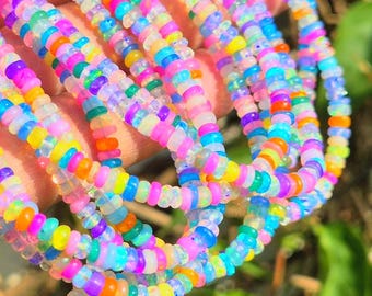 May include: A multi-strand necklace featuring small, round, translucent beads in a vibrant spectrum of neon colors including pink, orange, yellow, green, blue, and purple. The beads have a smooth, polished finish and are strung together in multiple rows.