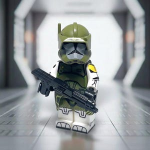 May include: A Lego minifigure of a soldier in olive green and white armor, holding a black rifle. The helmet has a unique design with a visor and antenna. The figure stands in a futuristic hallway setting.