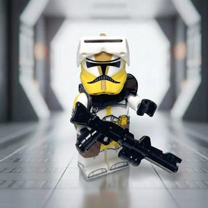 May include: A Lego minifigure of a clone trooper in white and yellow armor, holding a black blaster rifle. The helmet is white with a visor, and the trooper has a black neck guard. The background is a blurred, futuristic corridor.