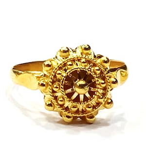 Puede incluir: Un anillo de oro con un diseño floral detallado. El anillo está hecho de una sola pieza de metal y tiene un acabado liso y pulido.