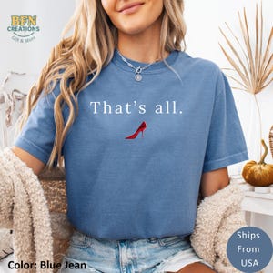 May include: Blue jean colored t-shirt with the text "That's all." and a red high heel graphic. The shirt is a crew neck style and has a relaxed fit. The image also includes the text "Ships From USA".