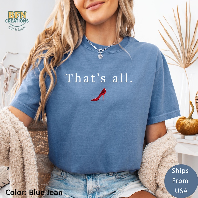 May include: Blue jean colored t-shirt with the text "That's all." and a red high heel graphic. The shirt is a crew neck style and has a relaxed fit. The image also includes the text "Ships From USA".