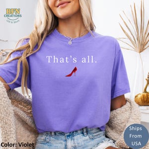 May include: Violet-colored t-shirt with the text "That's all." above a red high-heeled shoe graphic. The shirt has a relaxed fit and is made of a soft material. The shirt is a comfortable and stylish choice for casual wear.