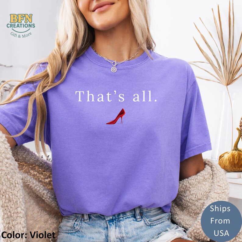 May include: Violet-colored t-shirt with the text "That's all." above a red high-heeled shoe graphic. The shirt has a relaxed fit and is made of a soft material. The shirt is a comfortable and stylish choice for casual wear.