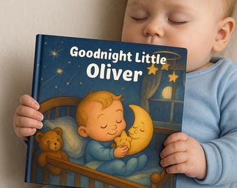 May include: A children's book titled "Goodnight Little Oliver" with a blue cover featuring an illustration of a baby in a crib with a teddy bear and a crescent moon. The book is held by a baby wearing a blue onesie.