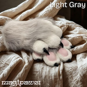 Puede incluir: Una pata peluda de color gris claro con almohadillas blancas y rosas y garras negras. El texto "Light Gray" está encima de la pata y "magipaws!" debajo.