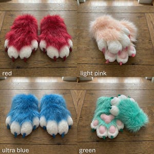 Puede incluir: Cuatro pares de zapatillas peludas con forma de pata en rojo, rosa claro, azul ultra y verde. Cada par tiene almohadillas y garras blancas. El par verde presenta un dise&ntilde;o en forma de coraz&oacute;n en las almohadillas. Se muestran sobre una superficie de madera.