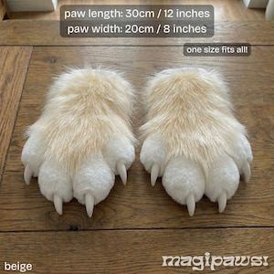 Puede incluir: Zapatillas de felpa beige con forma de pata y garras blancas. La longitud de la pata es de 30 cm y el ancho es de 20 cm. El texto "one size fits all!" es visible. La palabra "beige" est&aacute; en la parte inferior izquierda.