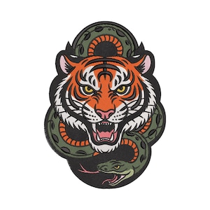 Puede incluir: Parche bordado con la cabeza de un tigre con rayas naranjas y negras, rodeada por una serpiente verde. El tigre tiene una expresión feroz con los dientes descubiertos. El parche tiene un borde negro.
