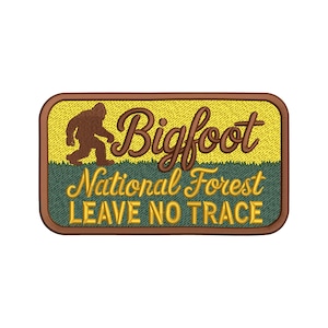 May include: Embroidered patch featuring a brown Bigfoot silhouette walking across a yellow and green background. The patch reads "Bigfoot National Forest LEAVE NO TRACE" in brown and yellow lettering. The patch has a brown border.