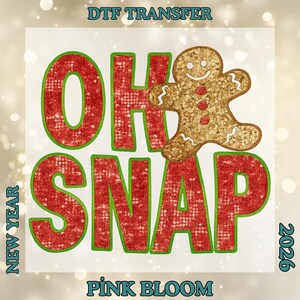 May include: A DTF transfer design with the words "OH SNAP" in red with green trim, and a gingerbread man. The words "NEW YEAR" and "2026" are on the sides, with "PINK BLOOM" at the bottom. The design is for the holiday season.