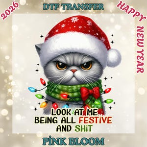 May include: A digital graphic of a grumpy gray cat wearing a Santa hat, a green scarf, and a string of colorful Christmas lights. Text on the image reads "LOOK AT ME BEING ALL FESTIVE AND SHIT" and "PINK BLOOM". The words "DTF TRANSFER", "2026", and "HAPPY NEW YEAR" are also present.