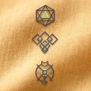 Peut inclure: Trois motifs géométriques en métal gris foncé avec des accents vert clair et dorés sont présentés sur un fond en tissu beige. Le motif supérieur est une étoile dans un hexagone. Le motif du milieu est une série de carrés connectés. Le motif inférieur est un cercle avec des symboles.