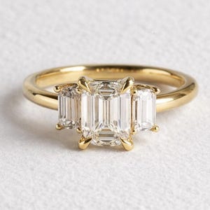 Förlovningsring med smaragdslipning och tre stenar, ring med baguettesidsten, ring med minimalistisk diamant i gult guld, löfte till brudparet