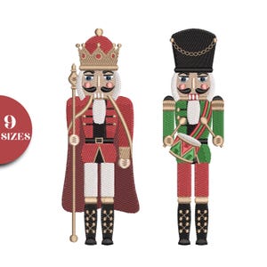 May include: Embroidered Christmas nutcracker designs. One nutcracker wears a red coat, crown, and holds a staff. The other wears a green jacket, black hat, and plays a drum. The designs are on a white background.