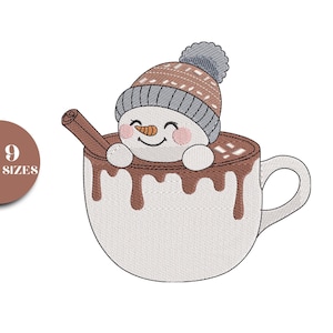 May include: An embroidered design of a snowman in a hot chocolate mug. The snowman wears a brown and gray knit cap and has rosy cheeks. A cinnamon stick rests on the edge of the mug. The mug is white with brown chocolate dripping down the sides.