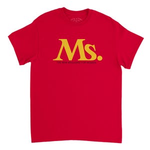 May include: A red t-shirt with the word "Ms." in gold lettering, with a gold dot, and the text "THE NEW MAGAZINE FOR WOMEN" below. The shirt is a solid red color.