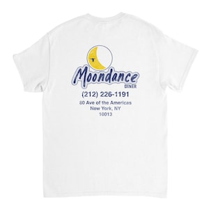 Puede incluir: Camiseta blanca con el texto "Moondance Diner" en azul y un gráfico de luna amarilla y azul. Debajo, el número de teléfono y la dirección del restaurante en Nueva York.