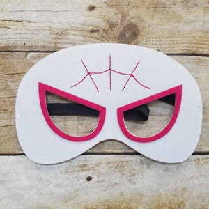 May include: White felt mask with pink eye holes and a black elastic band. The mask has a spider web design in the center.