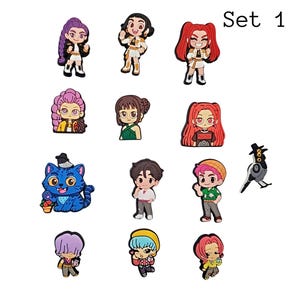 May include: Set of 12 colorful cartoon character charms. The charms feature various characters with different hairstyles, outfits, and accessories. There is also a blue cat charm and a bird charm. The text "Set 1" is in the upper right corner.