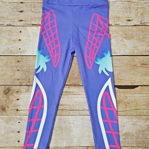 May include: Purple leggings with a white and pink design featuring a geometric pattern. The design is on the sides of the leggings.