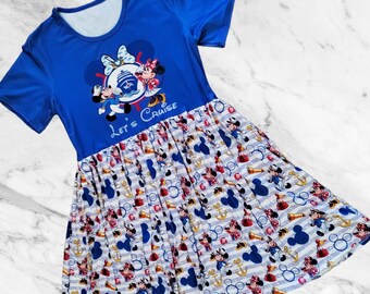 Könnte beinhalten: Blaues kurzärmeliges Kleid mit einem Mickey- und Minnie-Mouse-Motiv und dem Text "Let's Cruise". Der Rock hat ein Muster aus Mickey und Minnie Mouse, Ankern und nautischen Elementen auf gestreiftem Hintergrund.