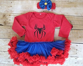 Könnte beinhalten: Ein roter Langarmbody mit einem schwarzen Glitzer-Spinnenemblem auf der Brust, kombiniert mit einem blauen Tüll-Tutu-Rock mit gerüschtem rotem Saum und einem passenden roten Häkel-Stirnband mit einer großen blauen Schleife und gelbem Akzent.