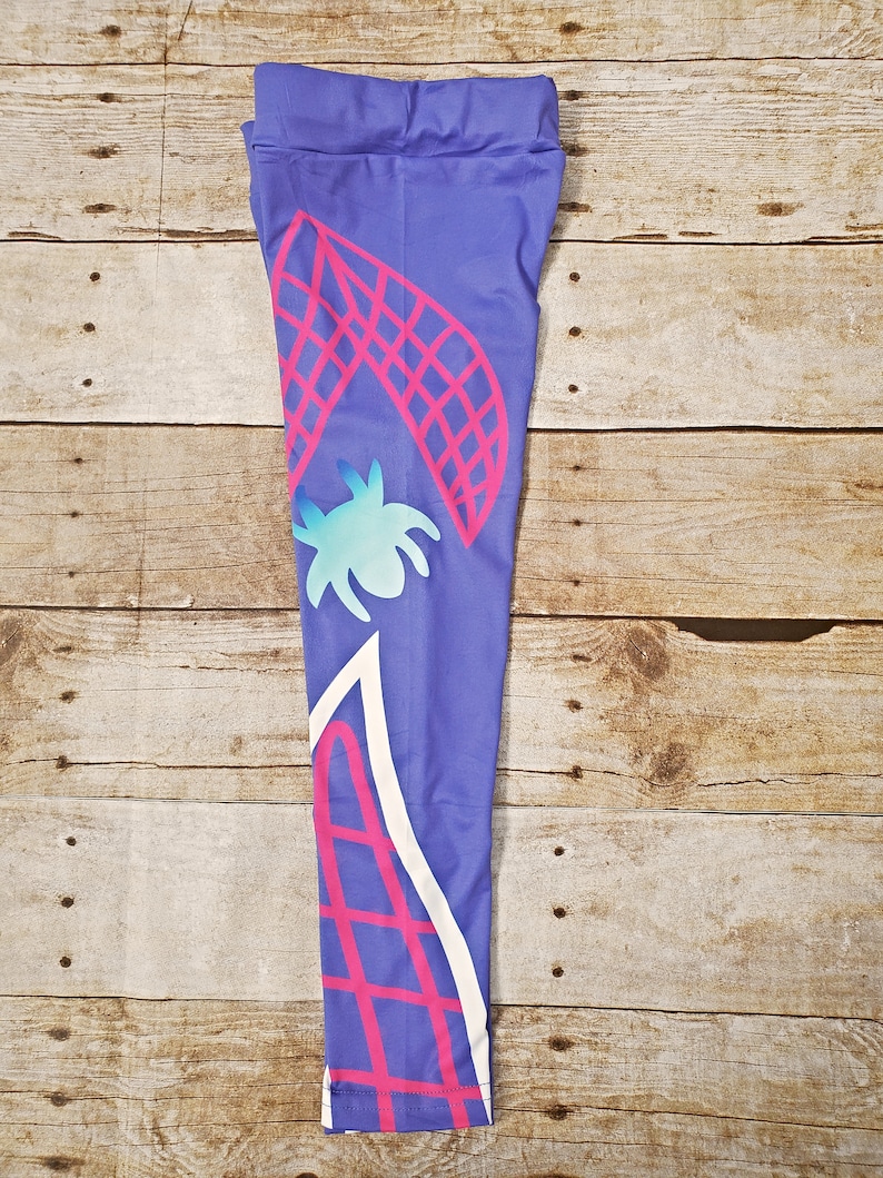 May include: Purple leggings with a pink and white geometric design. The design features a spider web and a stylized spider.
