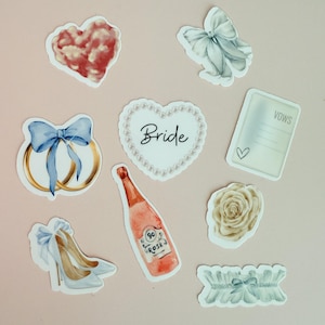 May include: A collection of watercolor-style stickers with a wedding theme. Includes a heart, bows, wedding rings, a heart-shaped sticker with the word "Bride", a bottle of rosé, a rose, a garter, a pair of high heels, and a vows card.