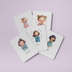 May include: A collection of white cards with illustrations of girls expressing different emotions. The cards include the words "Worried" and "Loved". The illustrations feature girls with various hairstyles and clothing, with soft color palettes and heart accents.